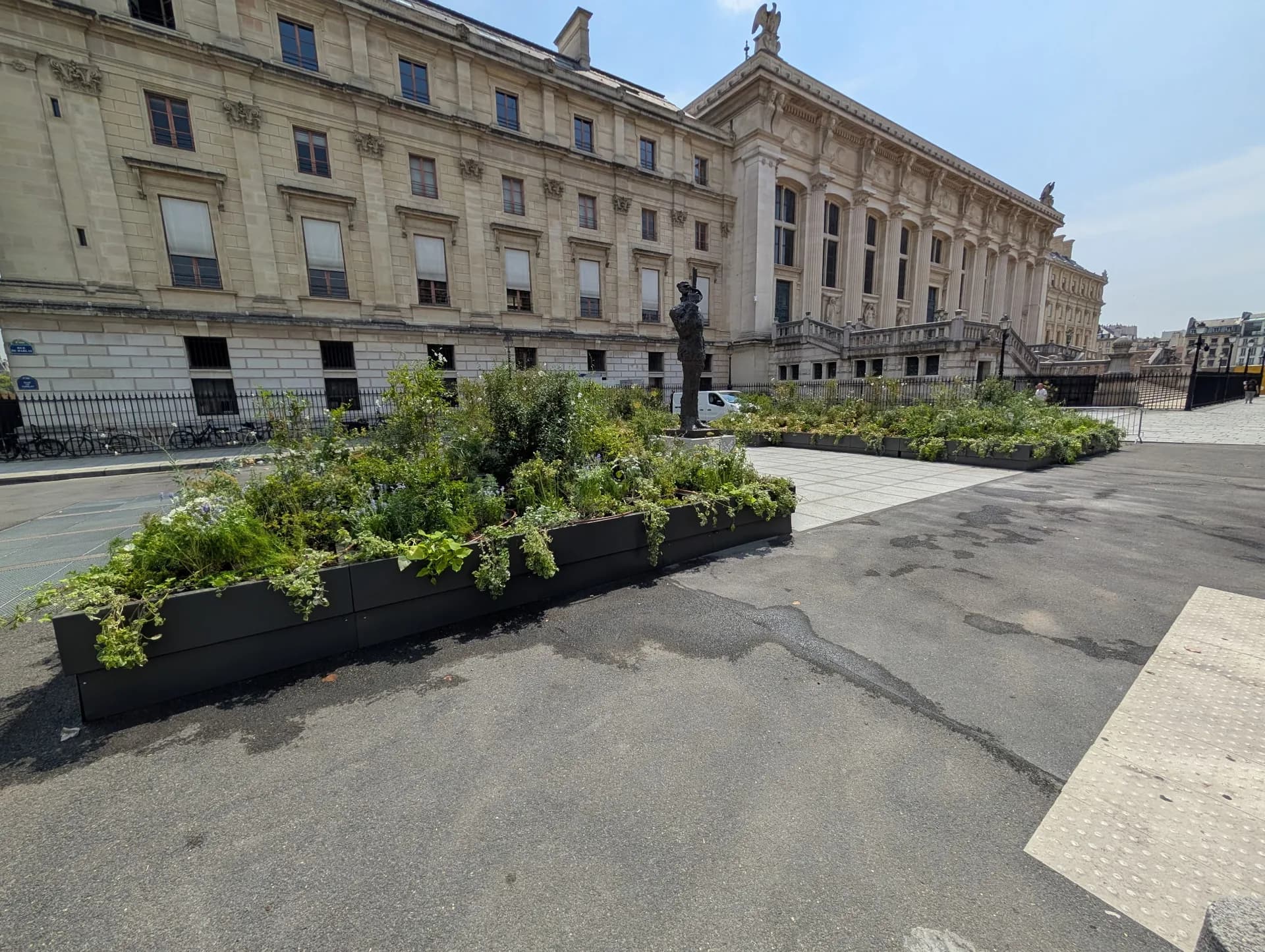 Vue latérale des bacs gris anthracite plantés devant la façade du Palais de Justice