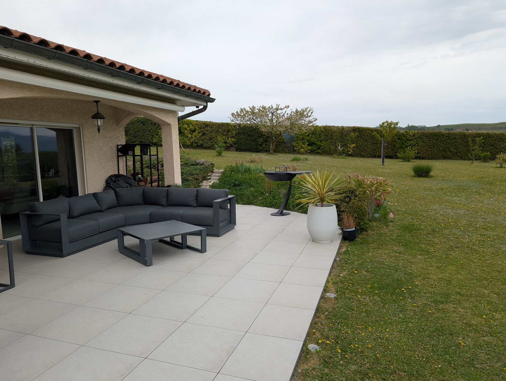 Brasero corten intégré à une terrasse avec salon de jardin