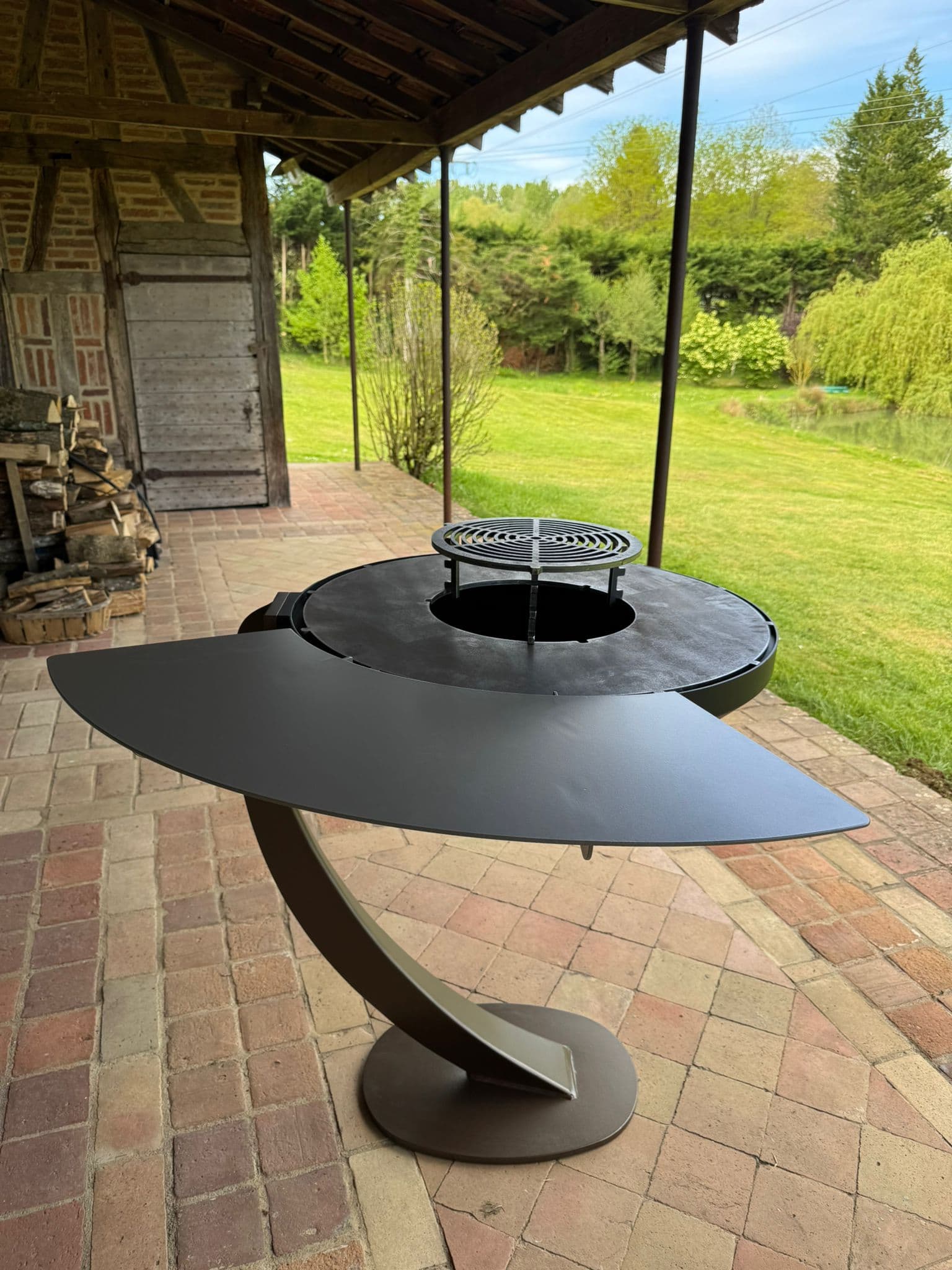 Brasero plancha avec tablette latérale déployée, ouverte sur un jardin verdoyant