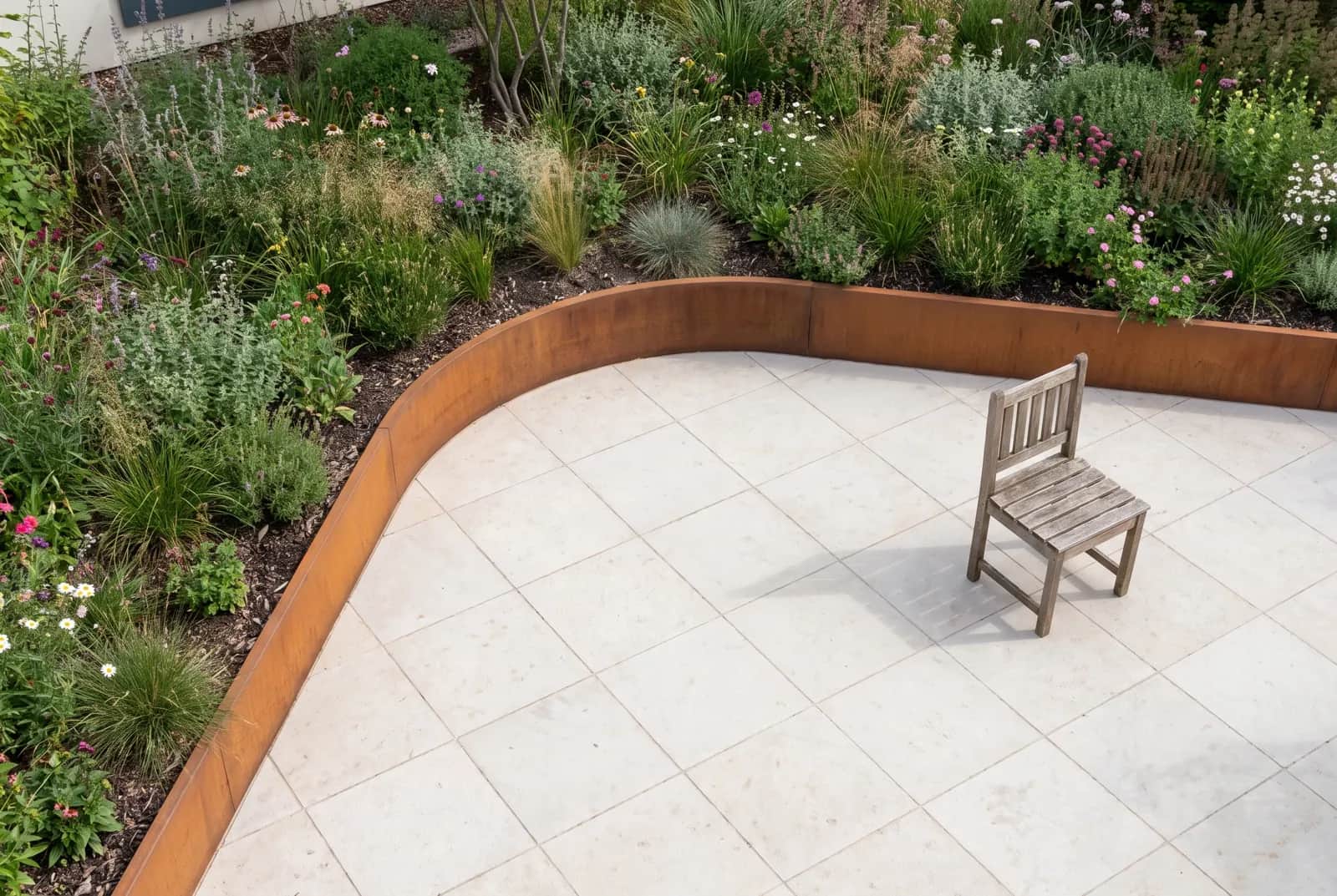 Courbe intérieure en Corten enveloppant une terrasse et un banc de jardin